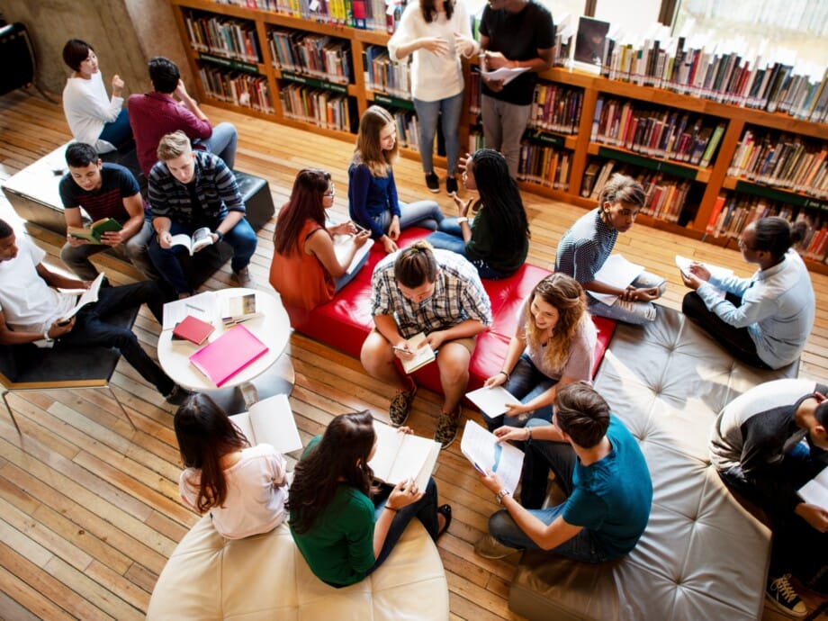 Diverse group of students studying in a library. Students reading, discussing, and collaborating. Library setting with books and study materials. High school students reading books in library.